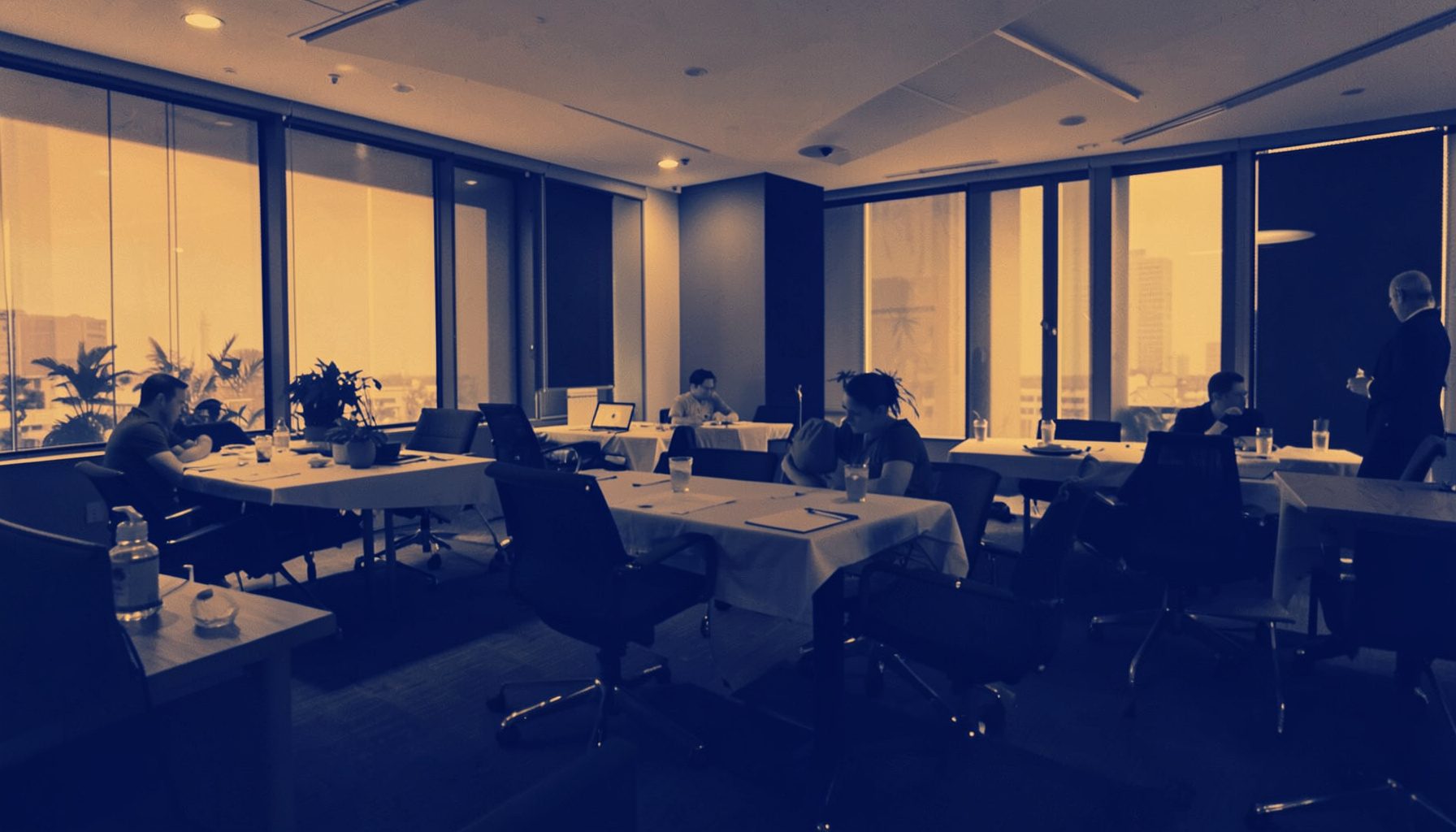 Soft duotone photograph of a conference networking lounge with warm amber and navy tones